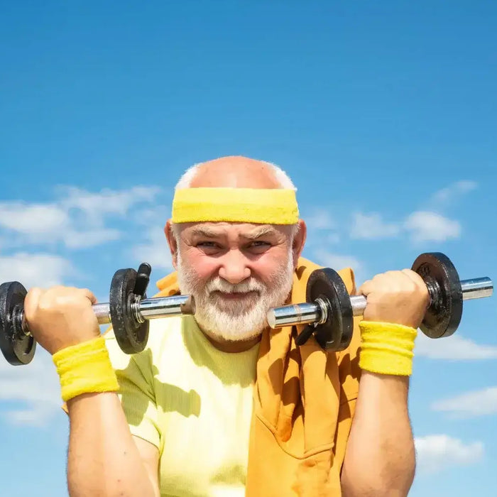 Older man exercising with dumbbells outdoors under a blue sky, representing vitality and health benefits of Tongkat Ali.