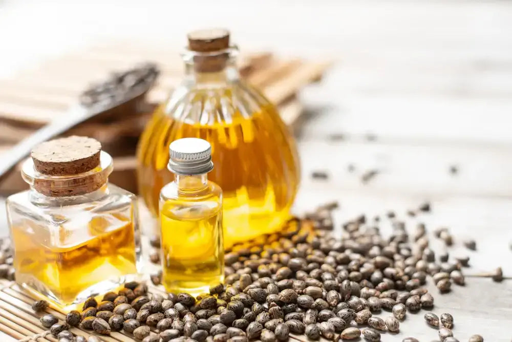 Bottles of castor oil with castor seeds on a wooden surface.
