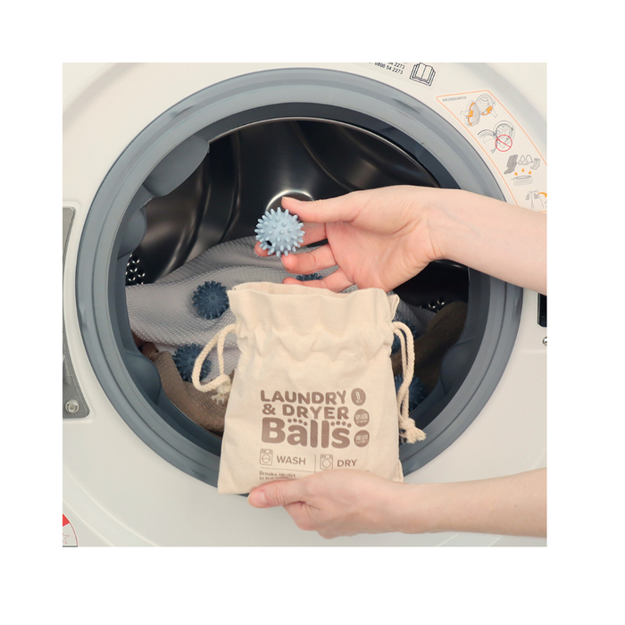 Person adding White Magic Eco Basics laundry balls to a dryer for quicker drying and softer clothes.