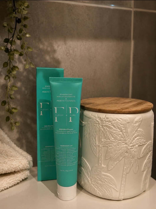 Flossy & Pure Mild Mint toothpaste tube and box in a bathroom setting